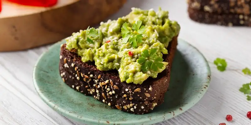Alcachofra e espinafres espalhados sobre um pão de grão
